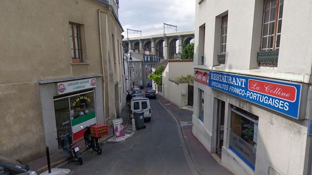 Rue du Docteur Vuillieme in Meudon, which is located to the south west of the centre of Paris, and about 6km from the Eiffel Tower. Tis is the earlier 2008 view of that road with the famous viaduct in the background. There is a pair of shops either side of the road. This was the nearest view to the site where André Kertész took his famous photograph that Google would show in 2013.