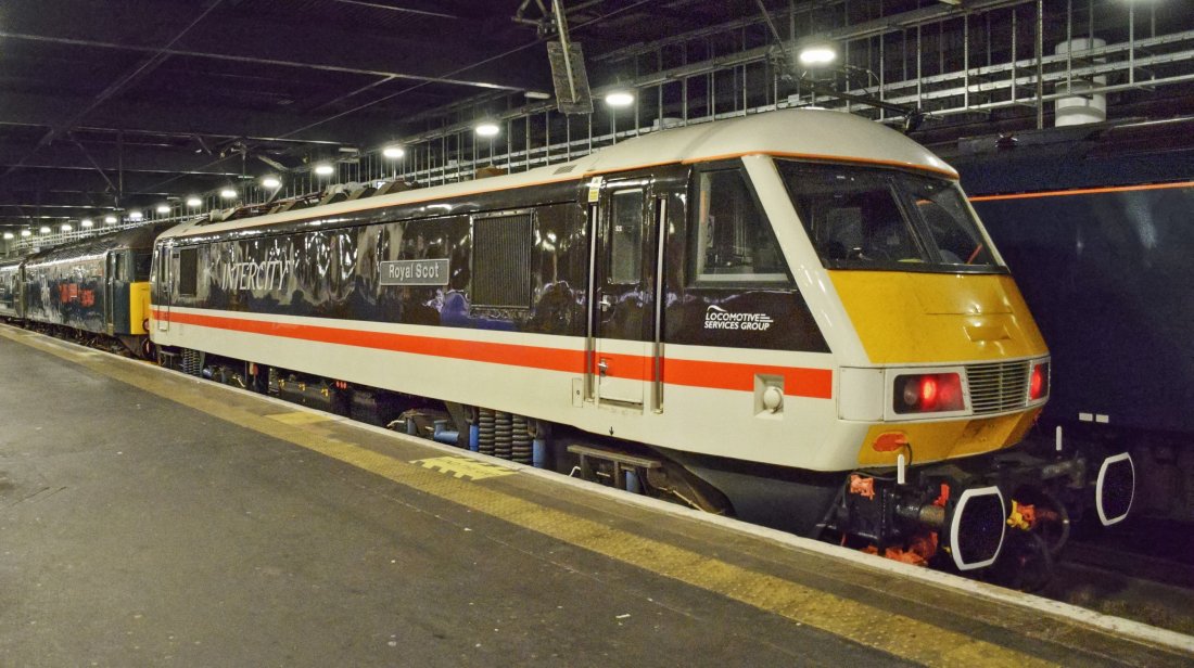 Class 90 at the London end of the GWR train providing power to the carriages. The name Royal Scot can be seen on the side of the locomotive. It is painted in Inter City colours (dark brown, white and red band along the side).