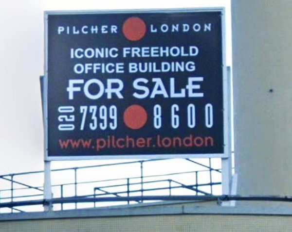 Sign says: Pilcher London iconic freehold office building for sale. 02073998600 www.pilcher.london