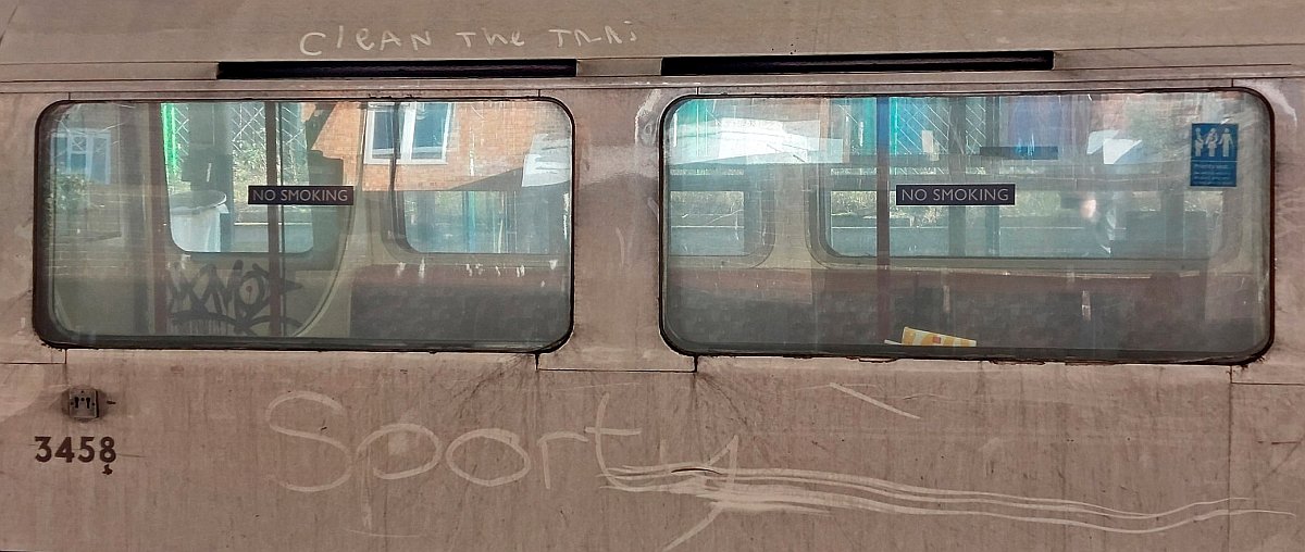 Clean the trai.... unfinished words seen on the upper side of the tube carriage - evidently someone was trying to convey a message that is perhaps felt by many as these incredibility dirty tube trains go about transporting Londoners. Below someone has written in large letters Sporty.