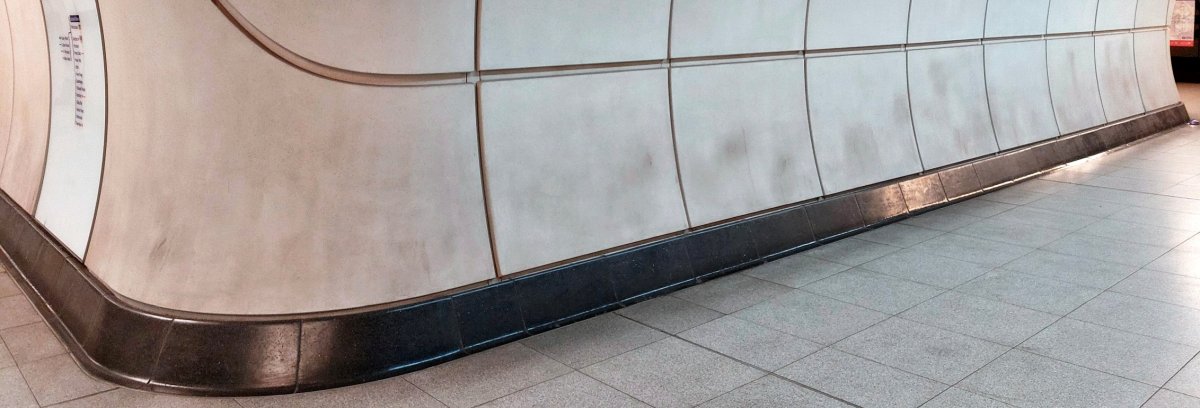 View of one of the interconnecting tunnels at Liverpool Street Elizabeth line showing many large patches of dirt. The eastbound platform is at right and a line diagram can be seen at left.
