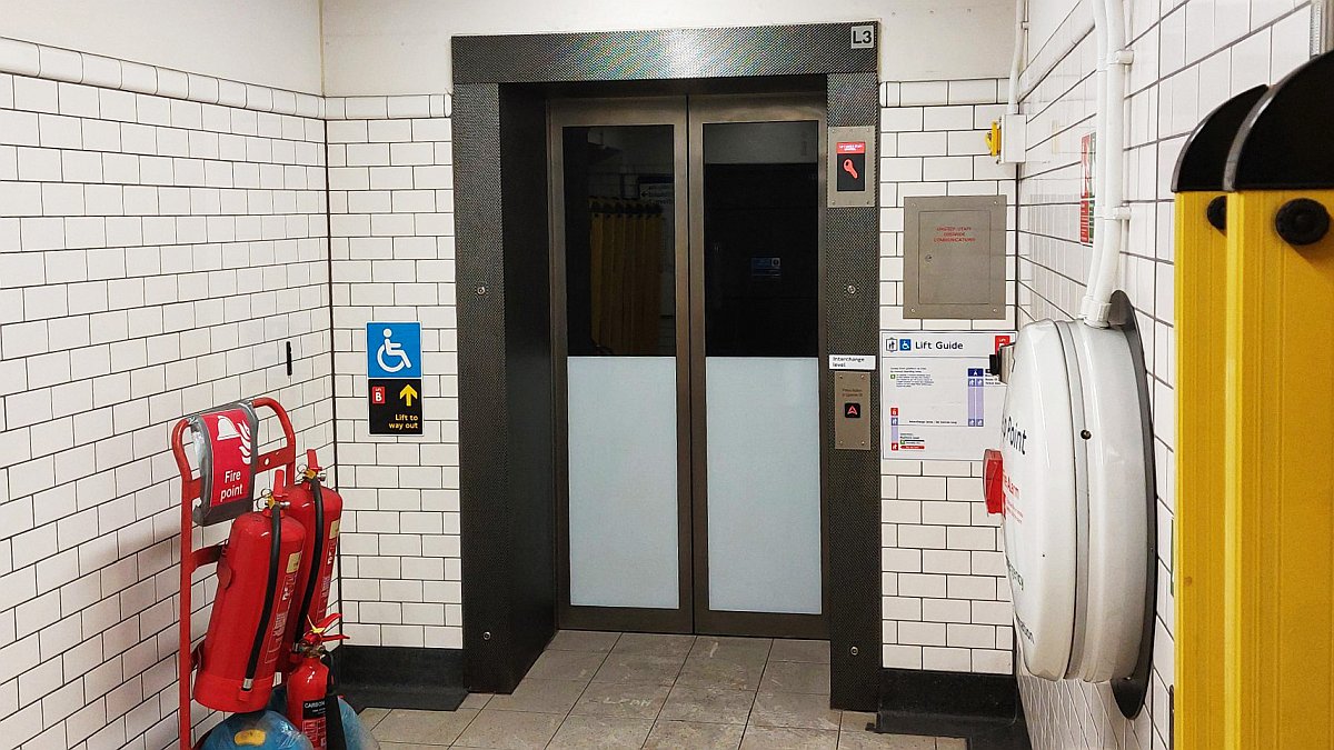 View of the new single lift at Knightsbridge. A help point can be seen and wheelchair symbols are visible. There are also fire extinguishers although it is expected these will be removed then the lifts open.