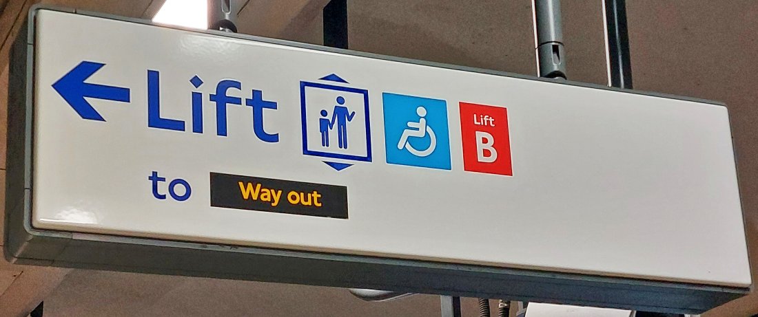 Sign saying 'Lift to Way out' with symbols showing lift, a wheelchair and the lift designation number eg 'B'.