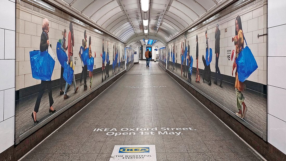 Advertising for the new Oxford Street IKEA store showing pictures of people carrying the iconic IKEA blue bags. Lettering on the floor says IKEA Oxford Street Open 1st May.