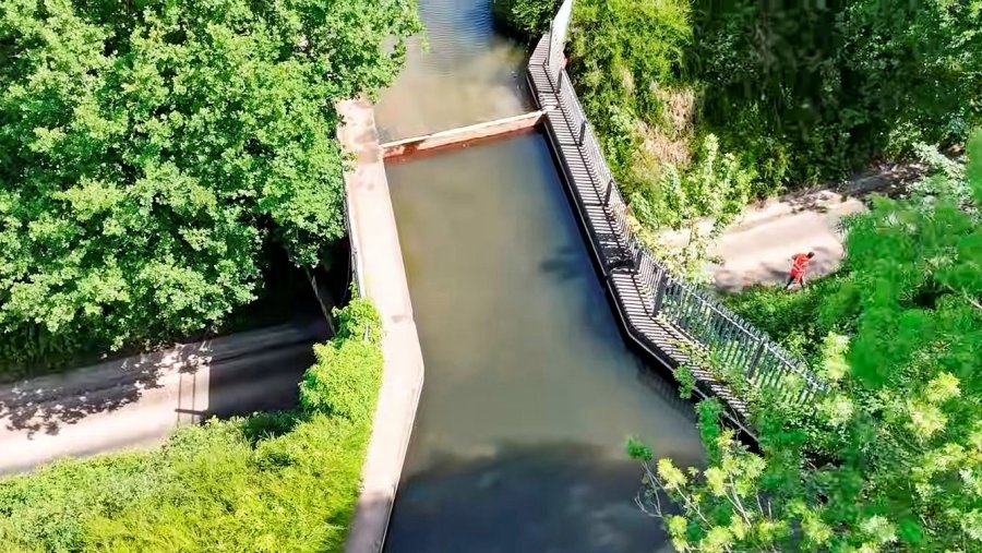 The new stop planks can be seen in place at Woodhouse Lane aqueduct. One worker who is seen in orange jacket at right is checking over the site before he leaves for home. There's a lot of greenery (trees etc) surrounding the aqueduct!