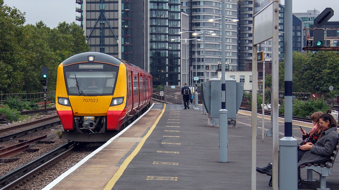 707023 seen at Vauxhall - there are people walking on the platform or sitting down and thumbing through their mobiles.