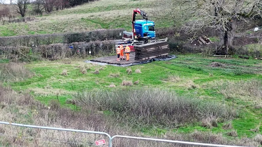 Peel Holdings' contractors in the field (seen near centre of picture) adjacent to Park Lane with a pile of wooden rafters - possibly intended for a temporary road or work area.